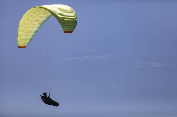 Een persoon met een parachute omhoog in de lucht op een blauwe hemel - Foto, afbeelding