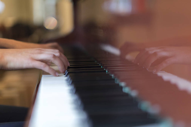Руки людини, що грає на коричневому грандіозному піаніно
 - Фото, зображення