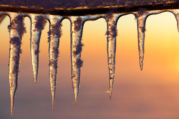 Buz sarkıtları batan güneşin yaktı. Seçici odak ve sığ derinlik-in tarla. - Fotoğraf, Görsel