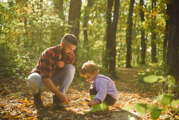Father and child son in autumn park having fun and laughing. Cute little boy with his father during stroll in the forest. - Foto, Imagen
