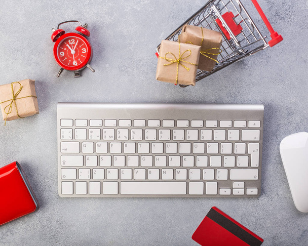 Concept online shopping buying presents. Red credit card, keyborad and christmas presents on grey table flat lay, copy space. Business christmas holidays concept, holiday gift online shopping concept. - Foto, Imagen