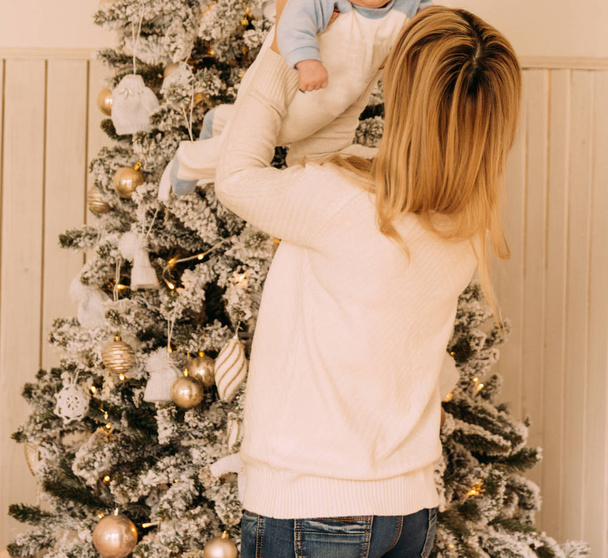 happy mother holding a small child in her arms opposite the Christmas tree.new Year - Фото, зображення