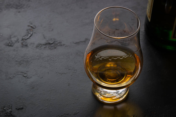 a glass of whiskey on a black background and space for text - Фото, изображение