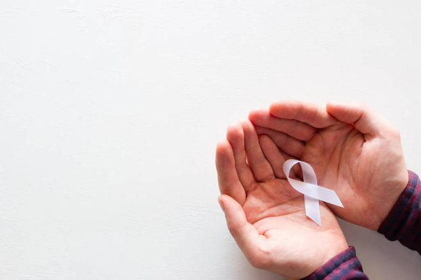man is holding a white ribbon on a white background with space for text - Photo, Image