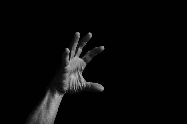 Men's hand reaches up out of the darkness to the light, in black and white. - Foto, Imagen