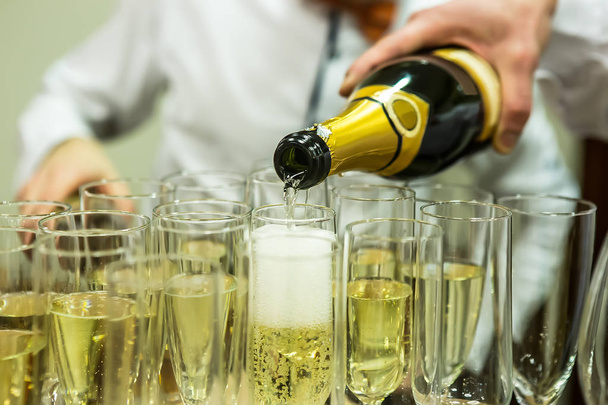 waiters pour champagne on glasses at a banquet - Foto, afbeelding