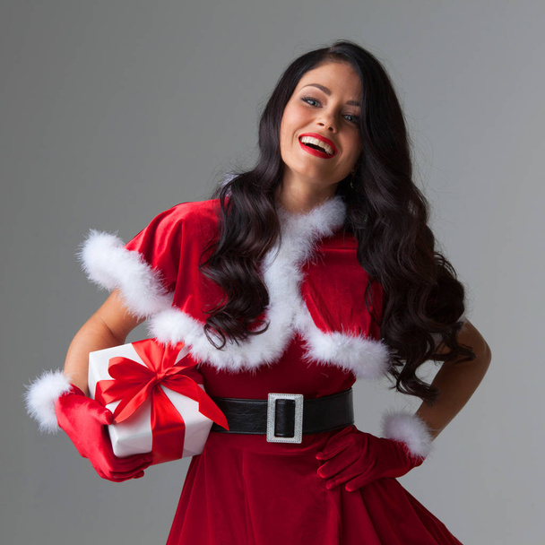 Woman in red Santa Claus outfit holding christmas gift box - Foto, afbeelding