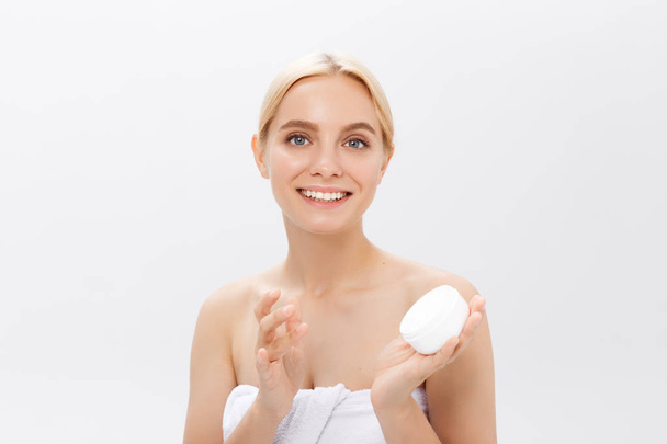 Primer plano retrato de belleza de una hermosa mujer medio desnuda riéndose aplicando crema facial aislada sobre fondo blanco
 - Foto, imagen