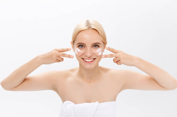 Close up beauty portrait of a laughing beautiful half naked woman applying face cream isolated over white background - Photo, Image