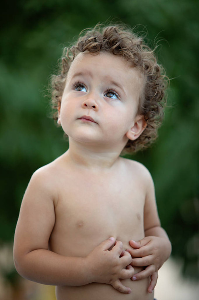 Красивый ребенок с вьющимися волосами в саду без футболки
 - Фото, изображение