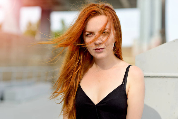Портрет девушки с рыжими волосами и зелеными глазами в ветреную погоду и солнечный летний день
 - Фото, изображение