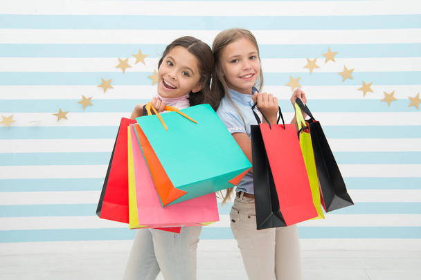 幸せな子供は、束のパッケージを運ぶ。最高の友人概念と買い物に。ショッピングのような女の子。子供たちの幸せな小さな女の子は、買い物袋を保持します。親友や妹とショッピングをお楽しみください。少女のような幸福 - 写真・画像