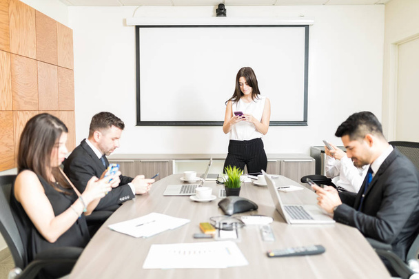 Multiethnische Geschäftsleute kommunizieren auf Smartphones im Sitzungssaal - Foto, Bild