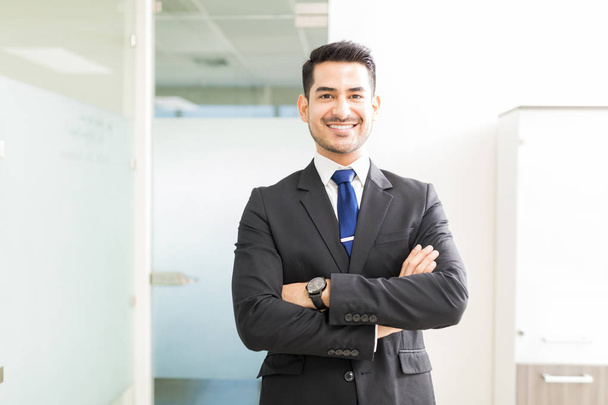 Young and powerful Hispanic lawyer standing arms crossed in office - Foto, imagen