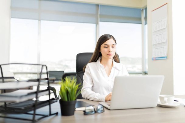 Серйозна жінка-адвокат перевіряє інформацію клієнта на ноутбуці за столом в офісі
 - Фото, зображення