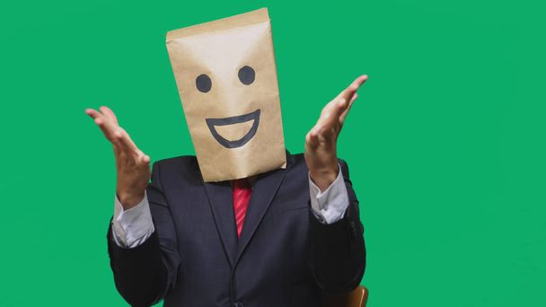 concepto de emociones, gestos. un hombre con bolsas de papel en la cabeza, con un emoticono pintado, sonrisa, alegría
 - Foto, imagen