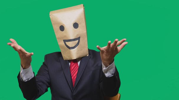 концепція емоцій, жестів. чоловік з паперовими мішками на голові, з пофарбованим смайликом, посмішкою, радістю
 - Фото, зображення