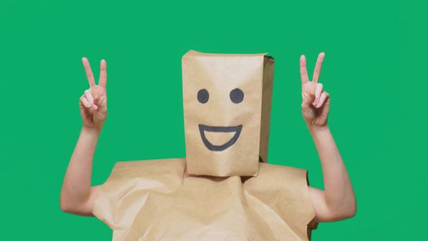 Konzept der Emotionen, Gesten. ein Mann mit Papiertüten auf dem Kopf, mit einem aufgemalten Emoticon, Lächeln, Freude - Foto, Bild