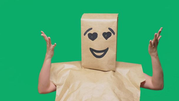 concept of emotions, gestures. a man with paper bags on his head, with a painted emoticon, smile, joy, love eyes. - Photo, Image