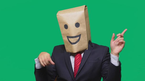 концепція емоцій, жестів. чоловік з паперовими мішками на голові, з пофарбованим смайликом, посмішкою, радістю
 - Фото, зображення