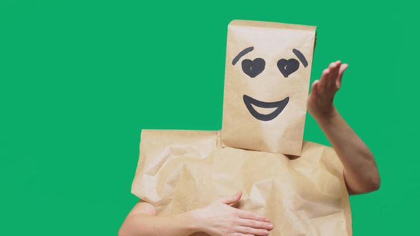 concept of emotions, gestures. a man with paper bags on his head, with a painted emoticon, smile, joy, love eyes. - Photo, Image