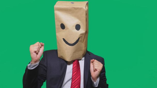 concept of emotions, gestures. a man with paper bags on his head, with a painted emoticon, smile, joy - Photo, Image