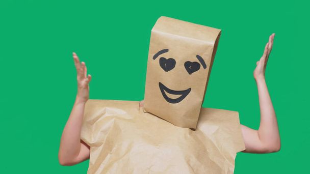 concept of emotions, gestures. a man with paper bags on his head, with a painted emoticon, smile, joy, love eyes. - Photo, image