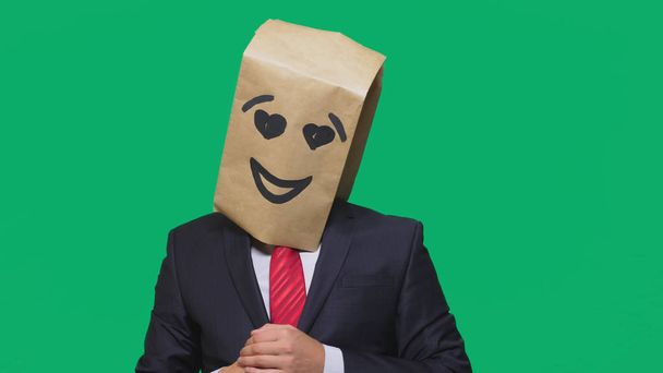 concept of emotions, gestures. a man with paper bags on his head, with a painted emoticon, smile, joy, love eyes. - Foto, afbeelding