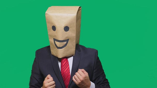 concepto de emociones, gestos. un hombre con bolsas de papel en la cabeza, con un emoticono pintado, sonrisa, alegría
 - Foto, Imagen