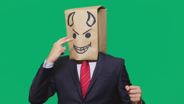 concept van emotie, gebaren. een man met een pakket op zijn hoofd, met een geschilderde smiley boos, sluwe, leedvermaak. - Foto, afbeelding