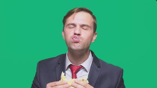 businessman eating a sandwich on a green background. quick lunch concept - Foto, Imagem