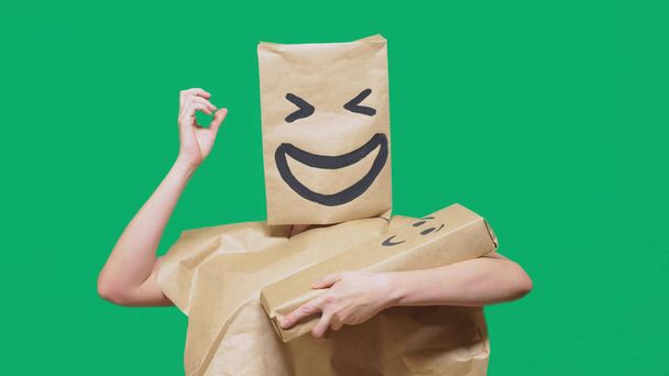 concept of emotions, gestures. man with a package on his head, with a painted emoticon, smile, joy, laughter. plays with the child painted on the box. - Fotoğraf, Görsel