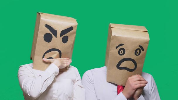 The concept of emotions and gestures. Two people in paper bags with smiles. Aggressive smiley swears. Second scared - Photo, Image