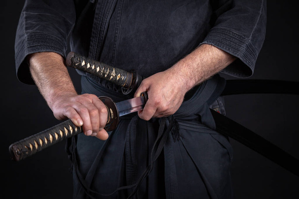 Самурай держит в руках японский меч катаны и катану на татами
 - Фото, изображение