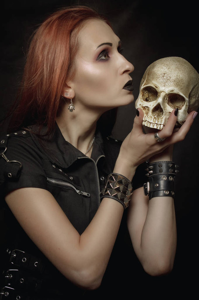Heavy metal girl with skull posing over dark background - Photo, Image