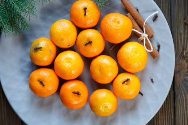 Ripe mandarine with leaves, tangerine  orange on wooden table background. Citrus fruits in plate with fir branches. Top view.   - Photo, Image