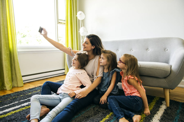 mother and daughters on the living room at home doing selfie, - Photo, Image