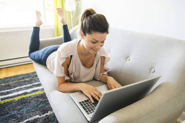woman with a laptop on sofa at home - Fotó, kép