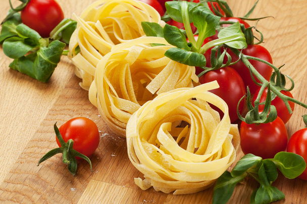 Tagliatelle pasta with fresh basil and tomatoes on rustic table - Valokuva, kuva