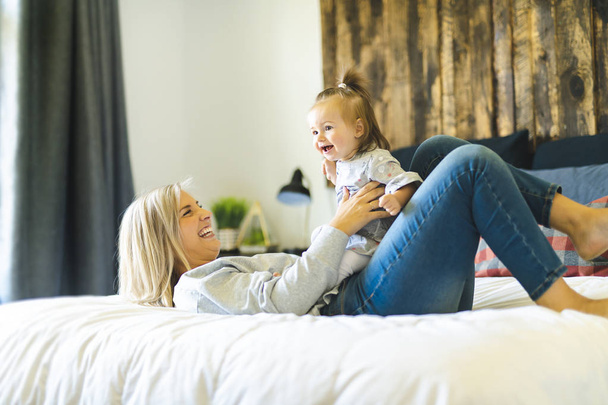 Mother and his baby daughter on bed having fun - Fotografie, Obrázek