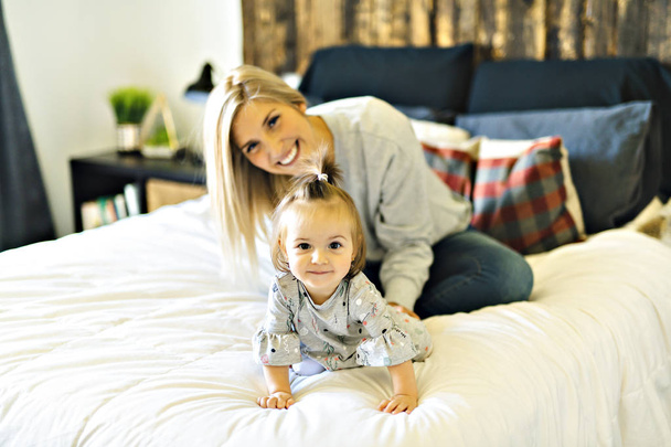 Mother and his baby daughter on bed having fun - Photo, Image