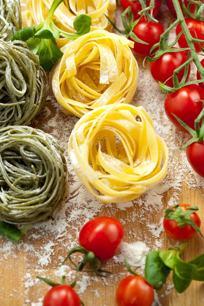 Tagliatelle pasta with fresh basil and tomatoes on rustic table - Фото, изображение