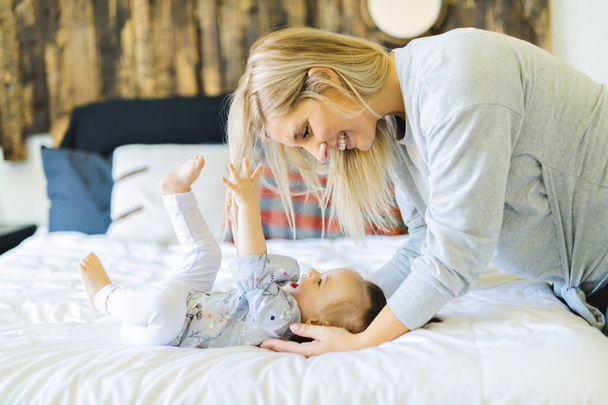 Mother and his baby daughter on bed having fun - Foto, immagini