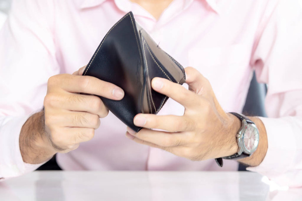 Мужчины смотрят на деньги в сумочке, бизнесмен держит пустой бумажник (без денег
) - Фото, изображение