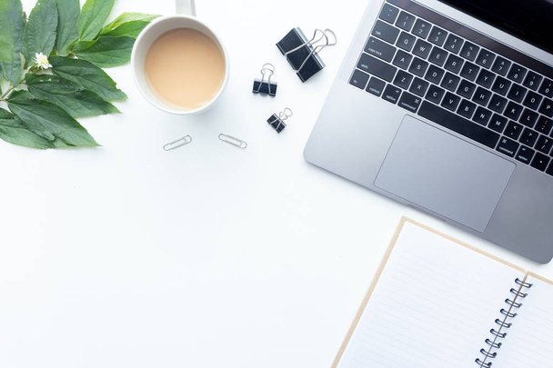 Bovenaanzicht werkruimte, laptop op witte tafel met koffie kopje en kantoor apparatuur op achtergrond - Foto, afbeelding
