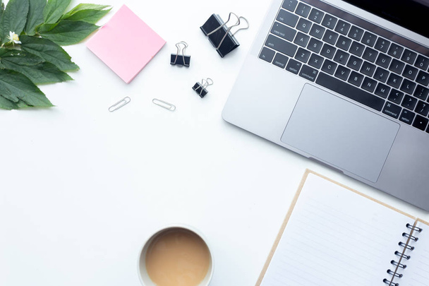 Pohled shora pracovní notebook na bílém stole s coffee cup a kancelářské vybavení na pozadí - Fotografie, Obrázek
