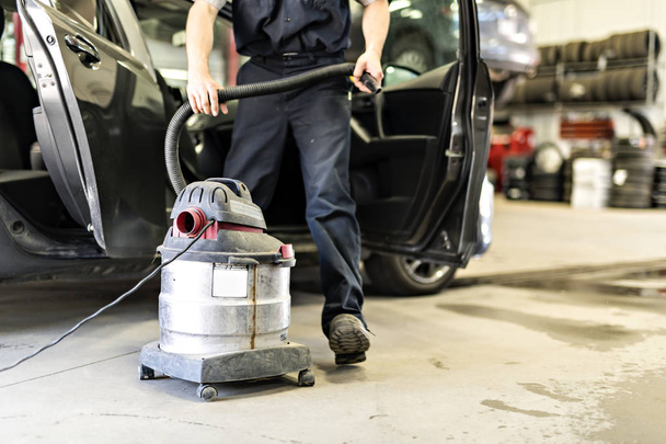 mechanic vacuuming the car at the garage - 写真・画像