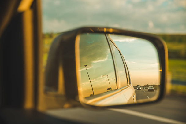 coche en la carretera. puesta de sol en el espejo del coche reflexión. viaje por carretera
 - Foto, imagen