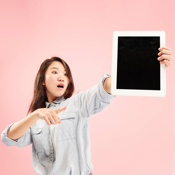 Portrait of a confident casual girl showing blank screen of laptop isolated over pink background - Foto, Imagem