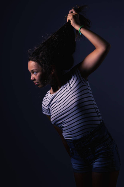Girl with striped t-shirt pulls her hair and goes towards the light. Concept - Photo, Image